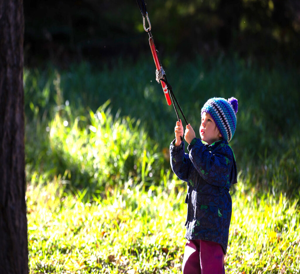 child playing outdoors with a rope attached to a tree