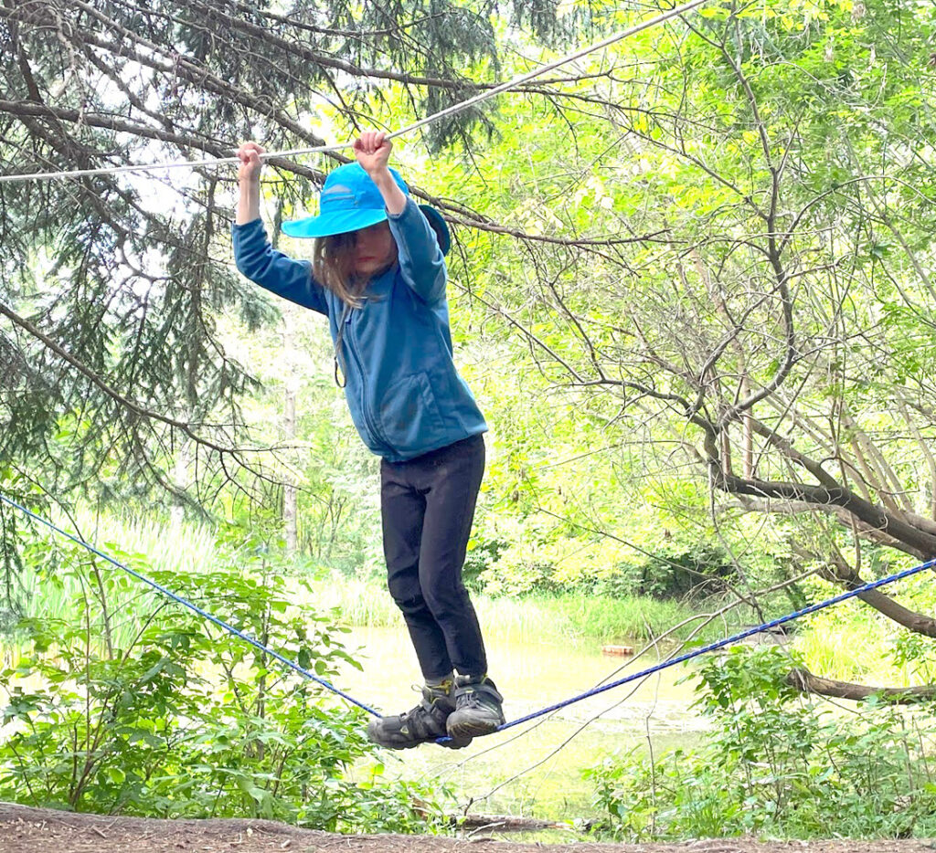 Child walking on outdoors ropes course in the forest