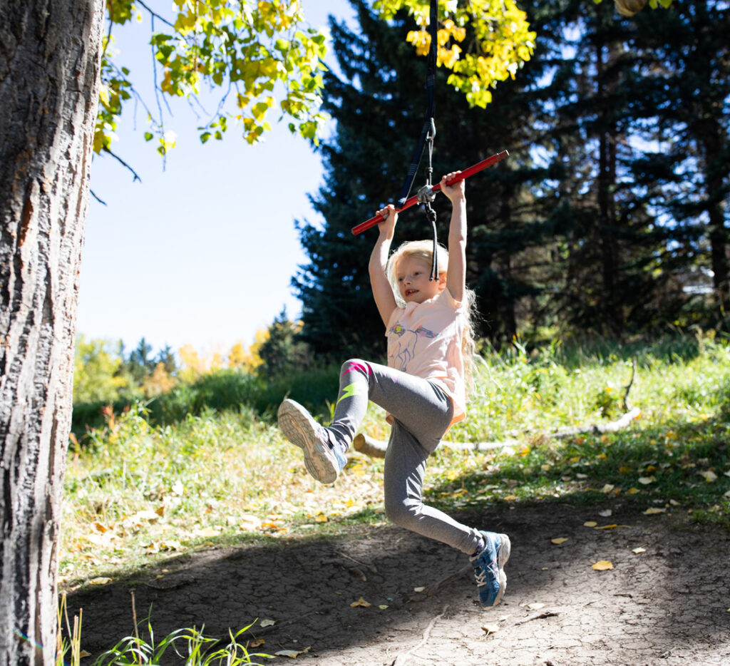 child swinging outdoors in a natural environment
